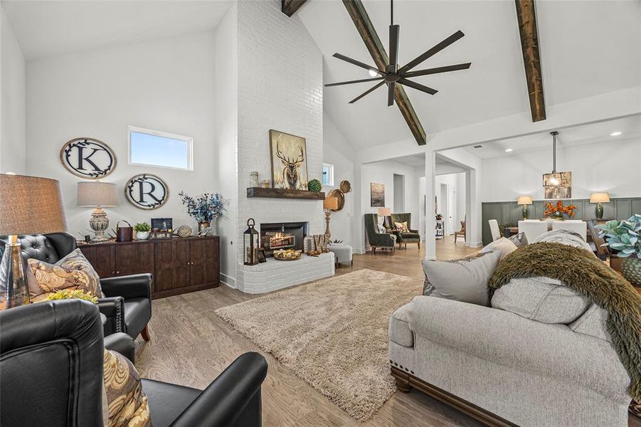 Living room with high vaulted ceiling, a fireplace, beam ceiling, and light wood-type flooring