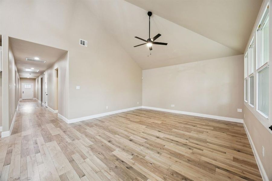 Unfurnished room featuring high vaulted ceiling, light wood-type flooring, and ceiling fan Unfurnished room featuring high vaulted ceiling, light wood-type flooring, and ceiling fan