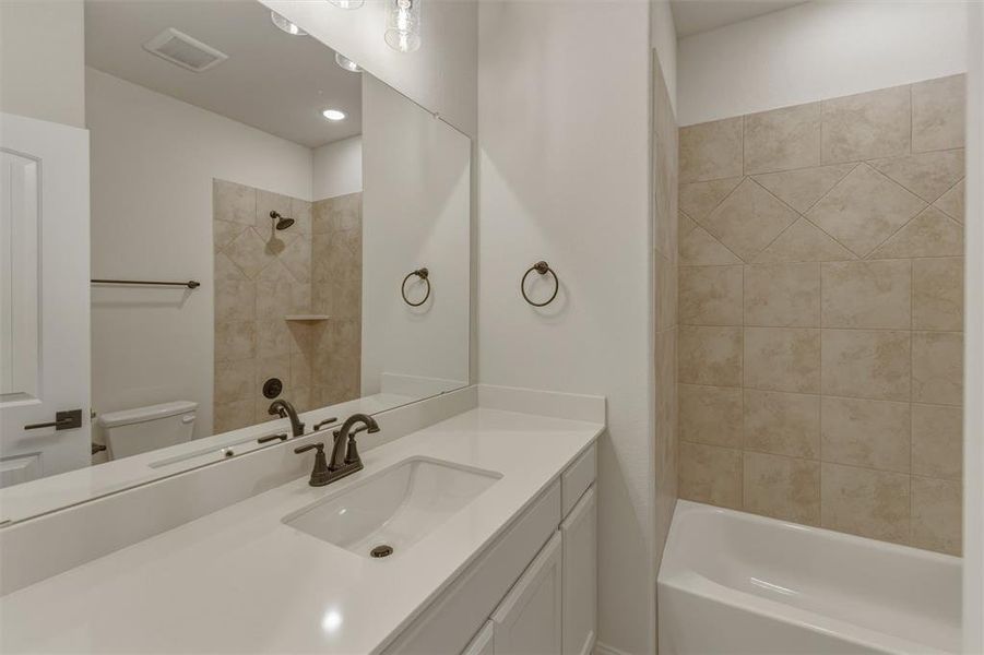 Bathroom featuring a white vanity with an integrated sink, bronze-finish faucet, and a large wall-mounted mirror Bathroom featuring a white vanity with an integrated sink, bronze-finish faucet, and a large wall-mounted mirror