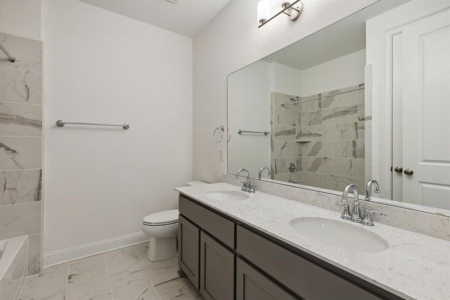 Bathroom featuring vanity, toilet, and tiled shower