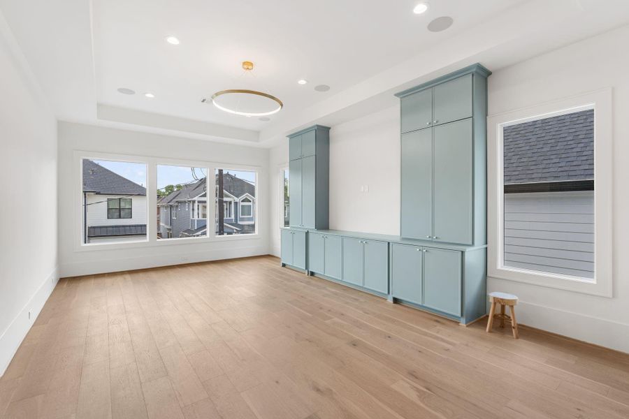 An expansive upstairs living area offers flexibility for a game room, media space, or secondary lounge, enhanced by large windows and custom built-in cabinetry.