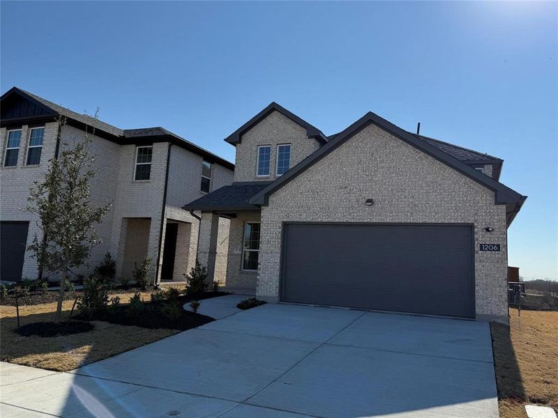 View of front of home with an attached garage, concrete driveway, and brick siding