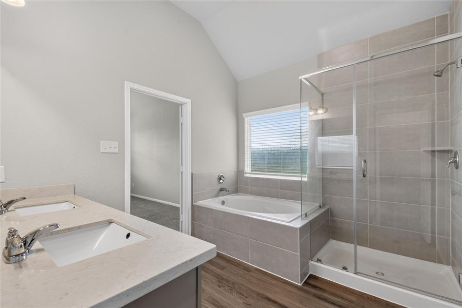 This modern bathroom features a double sink vanity, a spacious glass-enclosed shower, and a separate bathtub. The room is well-lit with natural light from a large window, and it has neutral tile and wood-look flooring. This modern bathroom features a double sink vanity, a spacious glass-enclosed shower, and a separate bathtub. The room is well-lit with natural light from a large window, and it has neutral tile and wood-look flooring.