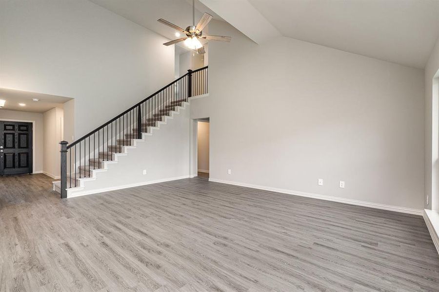 Unfurnished living room featuring ceiling fan, wood-type flooring, and high vaulted ceiling