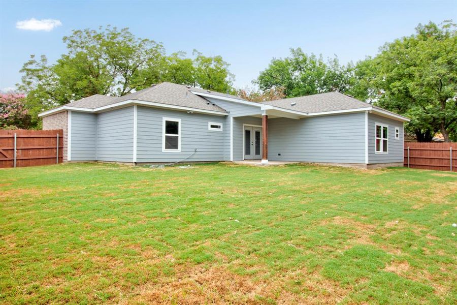 Rear view of property with a fenced backyard, a patio, french doors, and a shingled roof Rear view of property with a fenced backyard, a patio, french doors, and a shingled roof