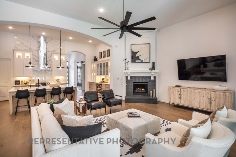 Living area featuring ceiling fan, arched walkways, wood finished floors, a brick fireplace, and recessed lighting Living area featuring ceiling fan, arched walkways, wood finished floors, a brick fireplace, and recessed lighting