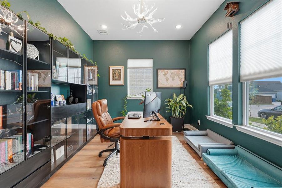 Dedicated office space featuring rich green walls, wood-finish flooring, and a contemporary antler-style chandelier Dedicated office space featuring rich green walls, wood-finish flooring, and a contemporary antler-style chandelier