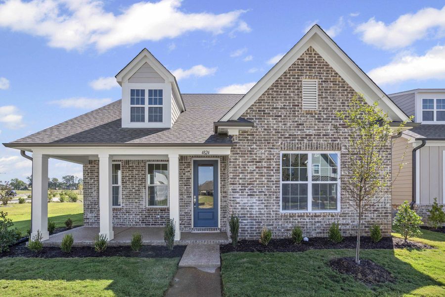 View of front of house with covered porch, a front yard, a shingled roof, and brick