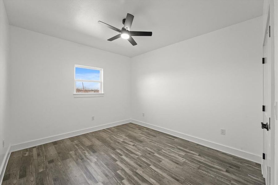 Unfurnished room featuring dark wood-type flooring and ceiling fan