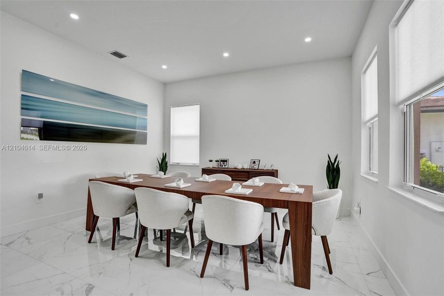 Recessed lighting, large windows, white walls, and marble look tile flooring