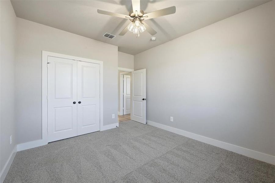 Unfurnished bedroom with carpet floors, ceiling fan, and a closet Unfurnished bedroom with carpet floors, ceiling fan, and a closet