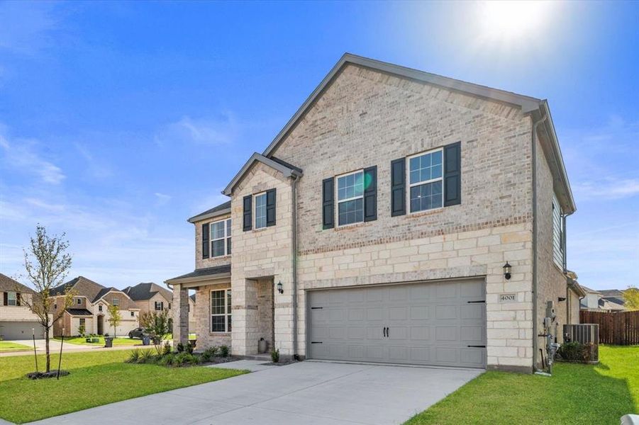 Traditional home featuring brick siding, a front yard, a garage, and concrete driveway
