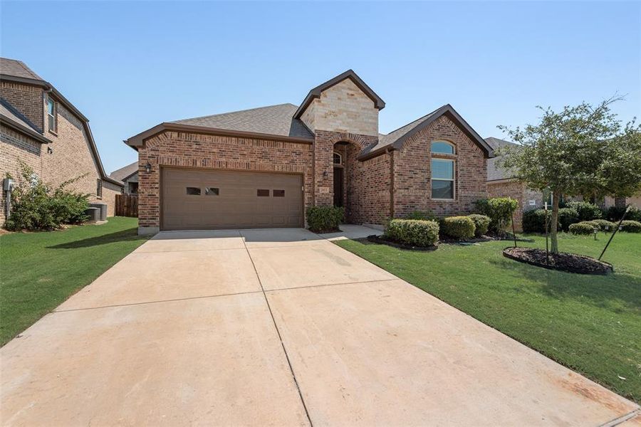 French country style house with brick siding, concrete driveway, an attached garage, a front lawn, and a shingled roof French country style house with brick siding, concrete driveway, an attached garage, a front lawn, and a shingled roof