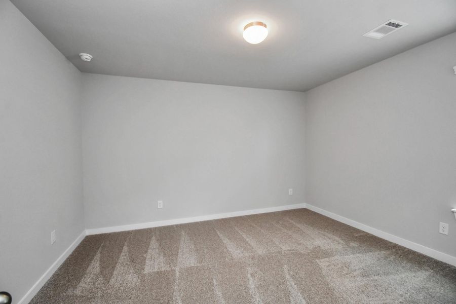 Secondary bedroom features plush carpeting, large windows that let in plenty of natural light, bright paint, and spacious closets. Sample photo of completed home with similar floor plan. Actual colors and selections may vary.