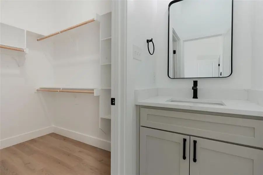 Bathroom with a spacious closet, vanity, and light wood-style floors