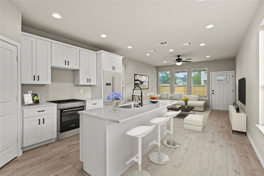 *Virtually Staged* Kitchen featuring stainless steel range oven, a center island with sink, white cabinetry, and sink