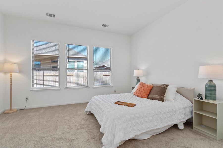 Bedroom featuring multiple windows and light carpet