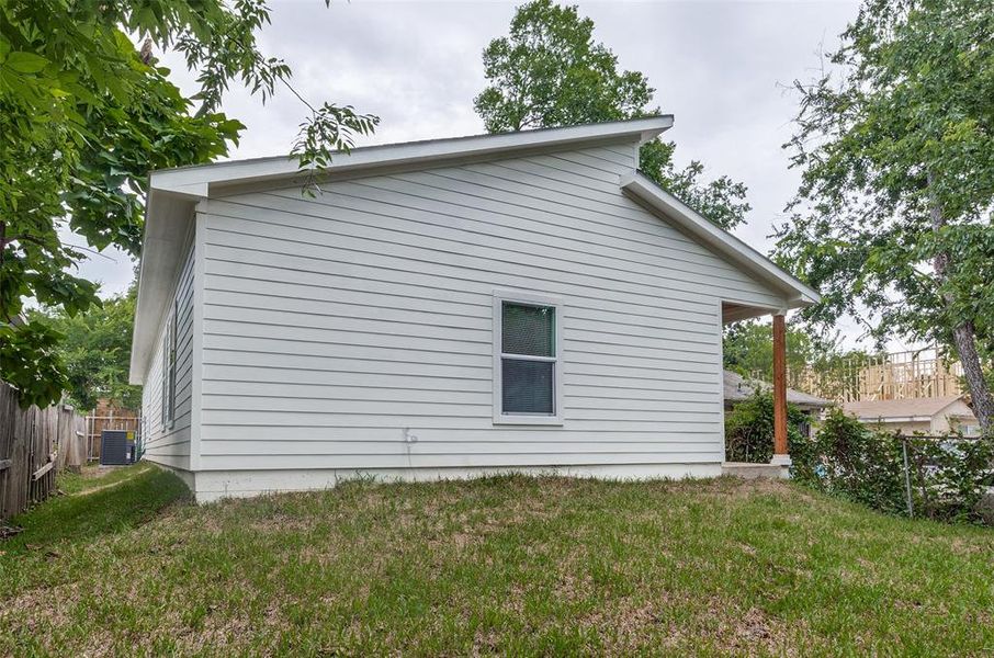 View of side of property featuring central AC and a lawn