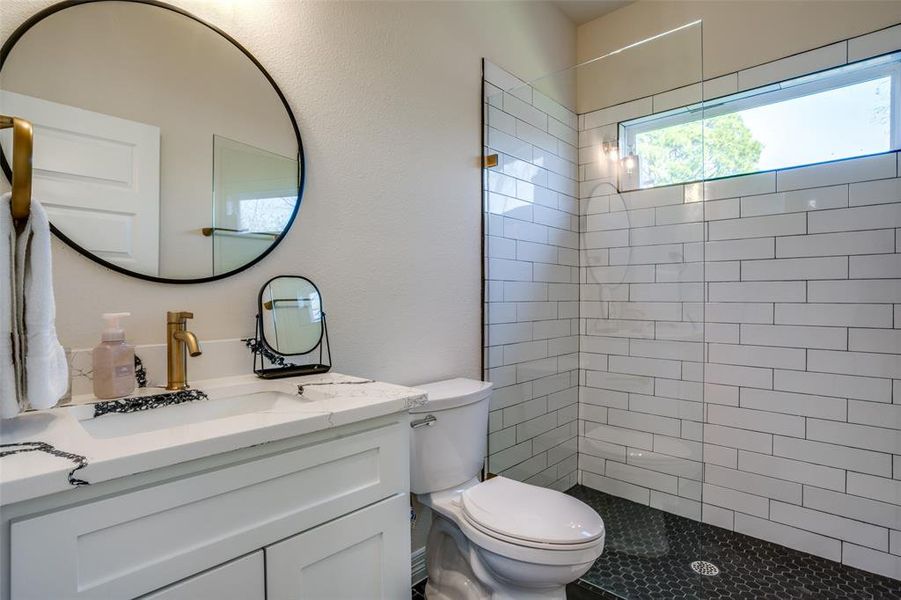 Bathroom with tiled shower, vanity, and toilet