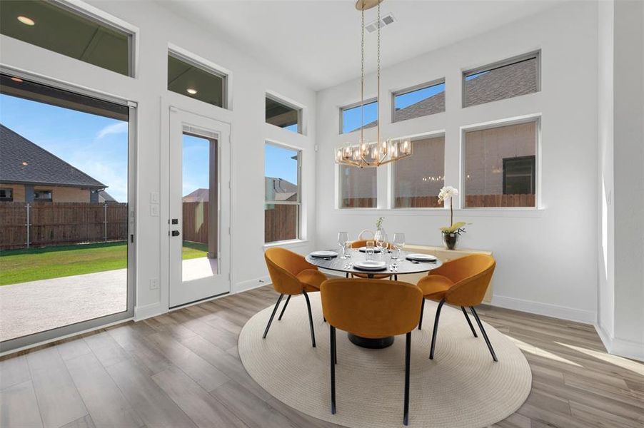 Dining area featuring wood-finish flooring, a contemporary linear chandelier, and expansive windows Dining area featuring wood-finish flooring, a contemporary linear chandelier, and expansive windows