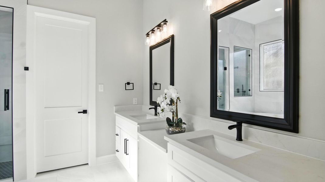 The framed mirrors and modern light fixtures create a perfect blend of style and function, offering excellent lighting and a high-end look. A central vanity area adds convenience and charm, ideal for personal grooming or décor accents. The framed mirrors and modern light fixtures create a perfect blend of style and function, offering excellent lighting and a high-end look. A central vanity area adds convenience and charm, ideal for personal grooming or décor accents.