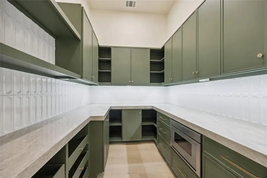 PANTRY: Even the oversized pantry is gorgeous and features extensive custom cabinetry, generous prep space, built-in microwave, and quartzite countertops for exceptional everyday functionality.