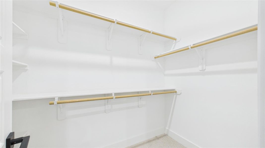 This spacious walk-in primary closet offers ample storage and organization, designed for both functionality and style. With generous shelving, hanging space, and well-placed lighting, it creates an elegant and practical wardrobe area. Thoughtfully designed to maximize convenience, this closet enhances the home's luxury and everyday comfort. This spacious walk-in primary closet offers ample storage and organization, designed for both functionality and style. With generous shelving, hanging space, and well-placed lighting, it creates an elegant and practical wardrobe area. Thoughtfully designed to maximize convenience, this closet enhances the home's luxury and everyday comfort.