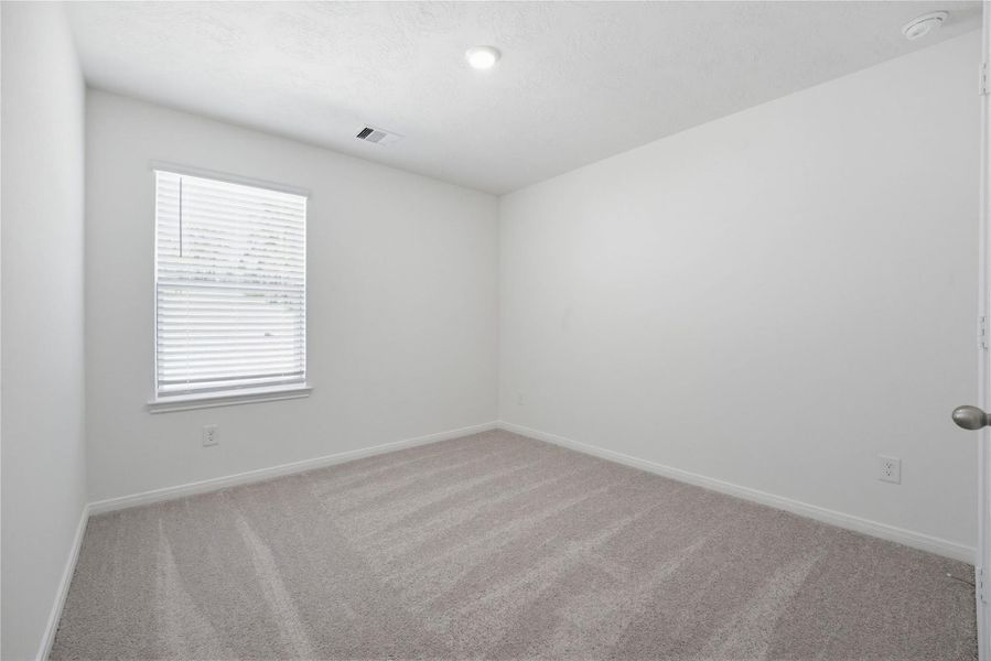 Secondary bedroom features plush carpet, neutral paint, lighting, large windows with privacy blinds, and ample sized closet space.