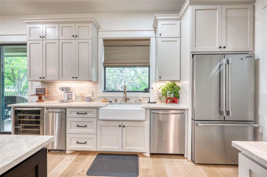 Modern kitchen featuring light-toned cabinetry, stainless steel appliances, and wood-finish flooring