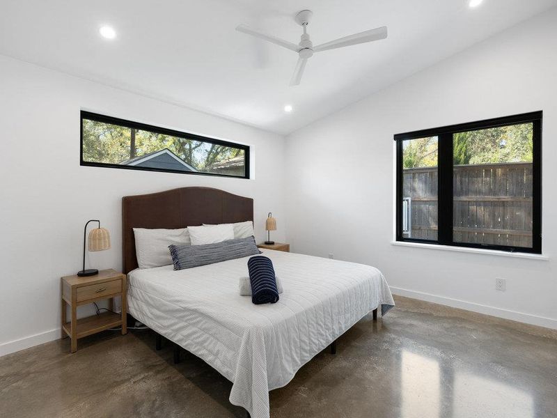 Bedroom featuring multiple windows, recessed lighting, lofted ceiling, finished concrete floors, and a ceiling fan