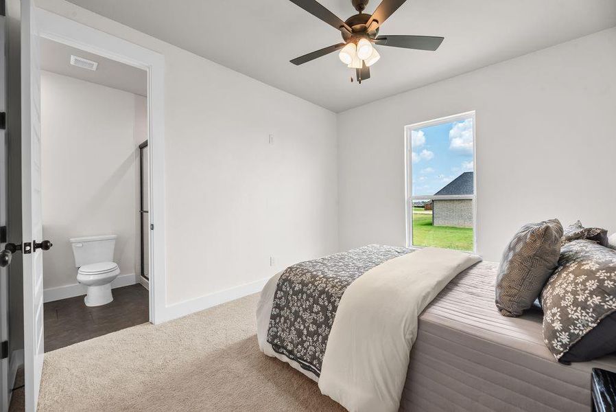 Bedroom featuring a ceiling fan, carpet floors, and ensuite bath Bedroom featuring a ceiling fan, carpet floors, and ensuite bath