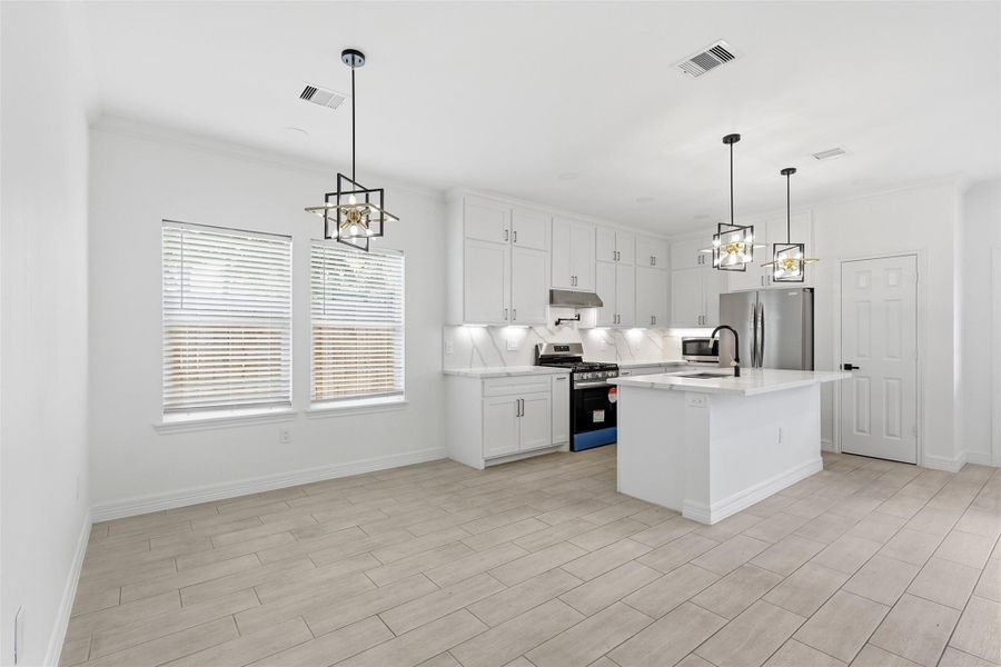 Gourmet kitchen featuring white cabinetry, pendant lighting, and an open layout perfect for entertaining.