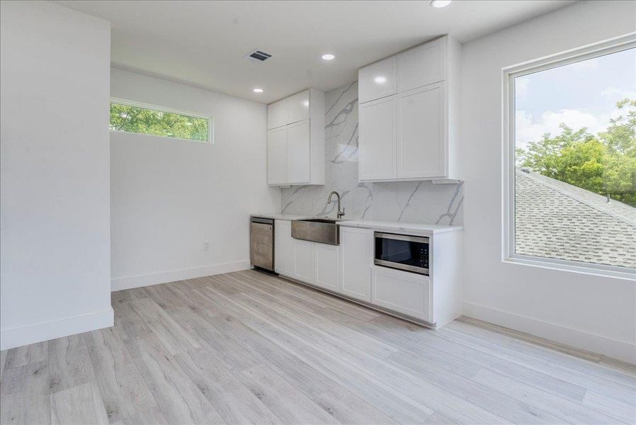 Kitchen with appliances with stainless steel finishes, light countertops, recessed lighting, white cabinetry, and light wood-style floors Kitchen with appliances with stainless steel finishes, light countertops, recessed lighting, white cabinetry, and light wood-style floors