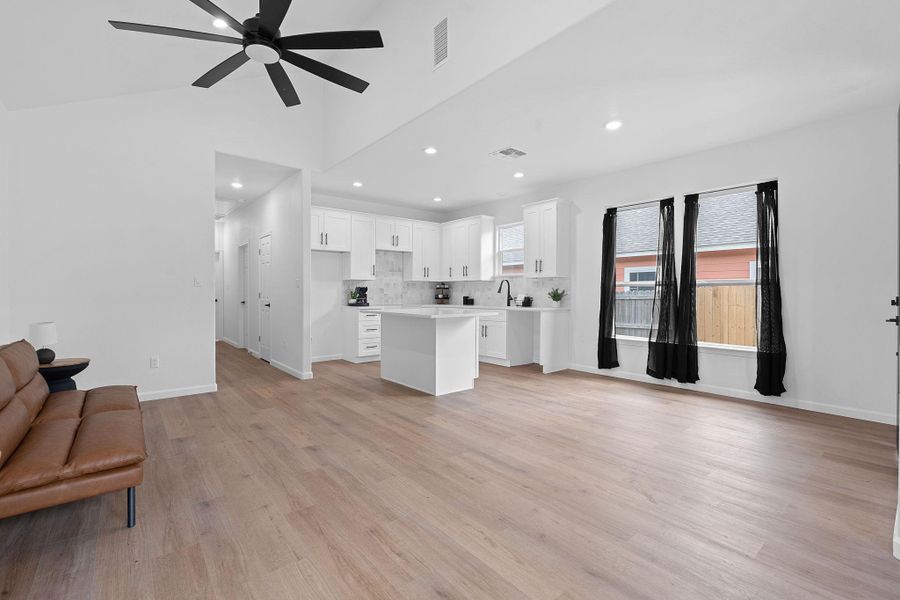 Unfurnished living room featuring ceiling fan, light wood-style flooring, recessed lighting, and lofted ceiling
