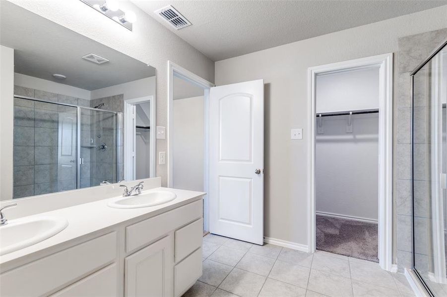 Bathroom featuring tile patterned floors, vanity, and walk in shower