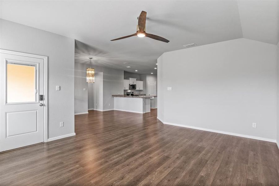 Unfurnished living room with dark hardwood / wood-style flooring, ceiling fan, and lofted ceiling