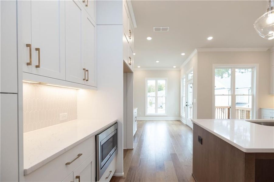 Kitchen with stainless steel microwave, hanging light fixtures, and white cabinets