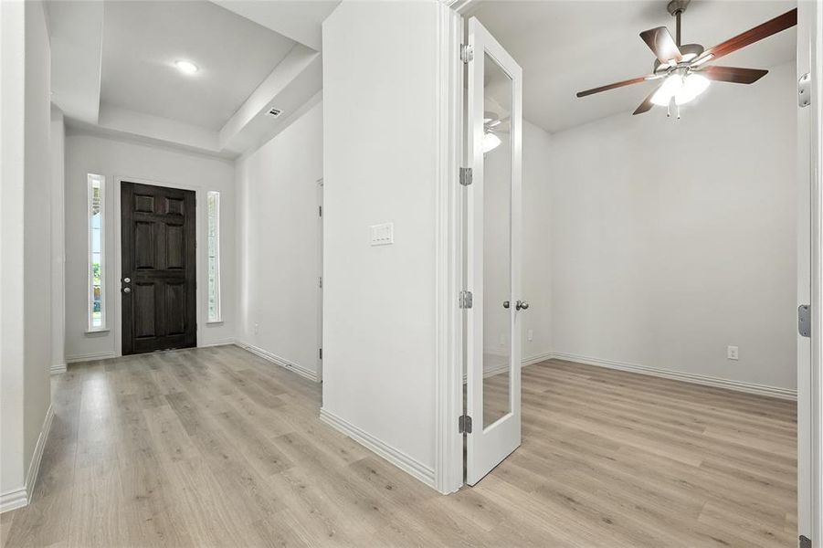 Entrance foyer with light wood-type flooring, a ceiling fan, a raised ceiling, and recessed lighting Entrance foyer with light wood-type flooring, a ceiling fan, a raised ceiling, and recessed lighting