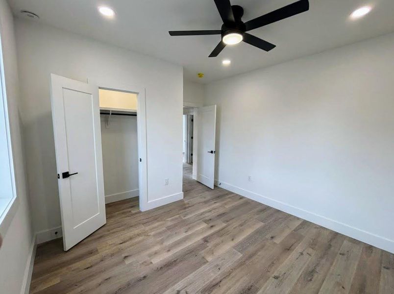 Unfurnished bedroom with light wood-style floors, a ceiling fan, recessed lighting, and a spacious closet