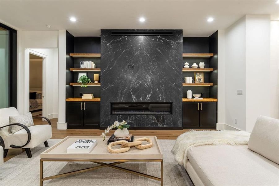 Living room with light hardwood / wood-style floors, a high end fireplace, and built in shelves