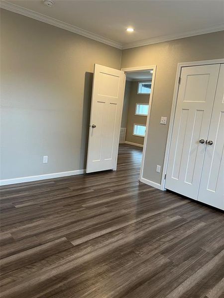 Unfurnished bedroom with crown molding, dark wood-type flooring, recessed lighting, and a closet