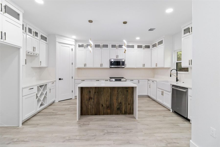 Kitchen featuring a kitchen island, light stone counters, light wood-type flooring, white cabinets, and recessed lighting