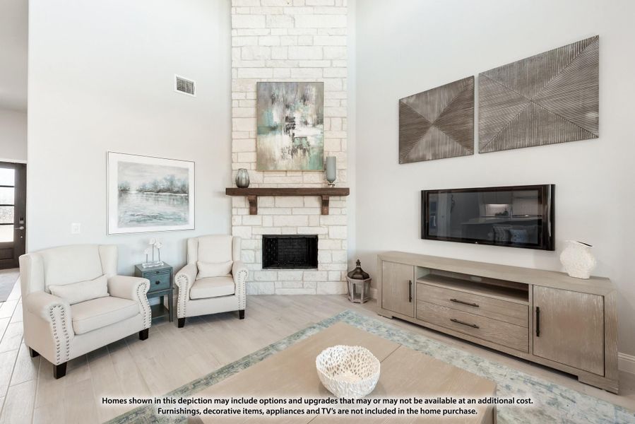 Living room with tall brick fireplace, two white armchairs, and a wood media console with wall-mounted TV