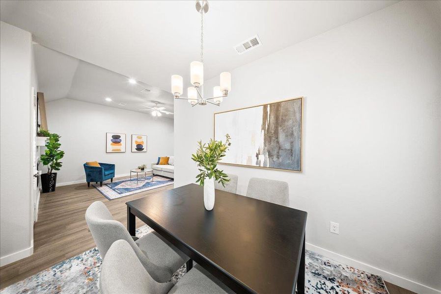 Dining room featuring wood finished floors, vaulted ceiling, a chandelier, and a ceiling fan Dining room featuring wood finished floors, vaulted ceiling, a chandelier, and a ceiling fan