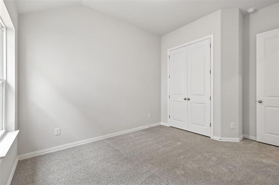 Unfurnished bedroom featuring carpet floors, a closet, and vaulted ceiling