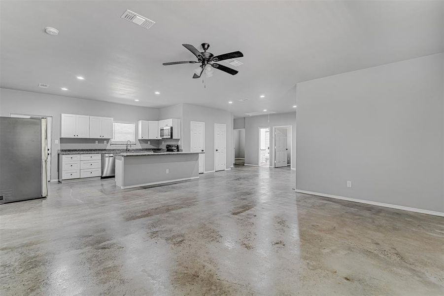 Unfurnished living room with sink, a wealth of natural light, and ceiling fan