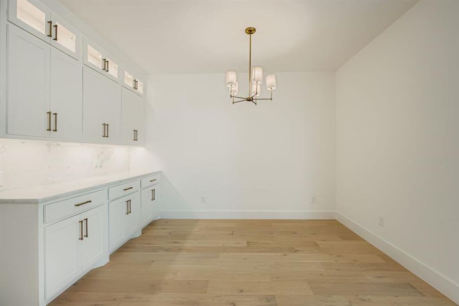 Unfurnished dining area with light wood-style flooring and a chandelier Unfurnished dining area with light wood-style flooring and a chandelier