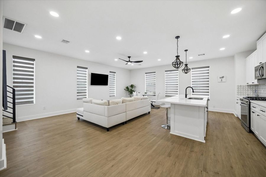 Main level lives as one open room, with kitchen, dining, and living all sharing the same plank flooring. Zebra shades cut the afternoon glare without closing off the windows. Main level lives as one open room, with kitchen, dining, and living all sharing the same plank flooring. Zebra shades cut the afternoon glare without closing off the windows.