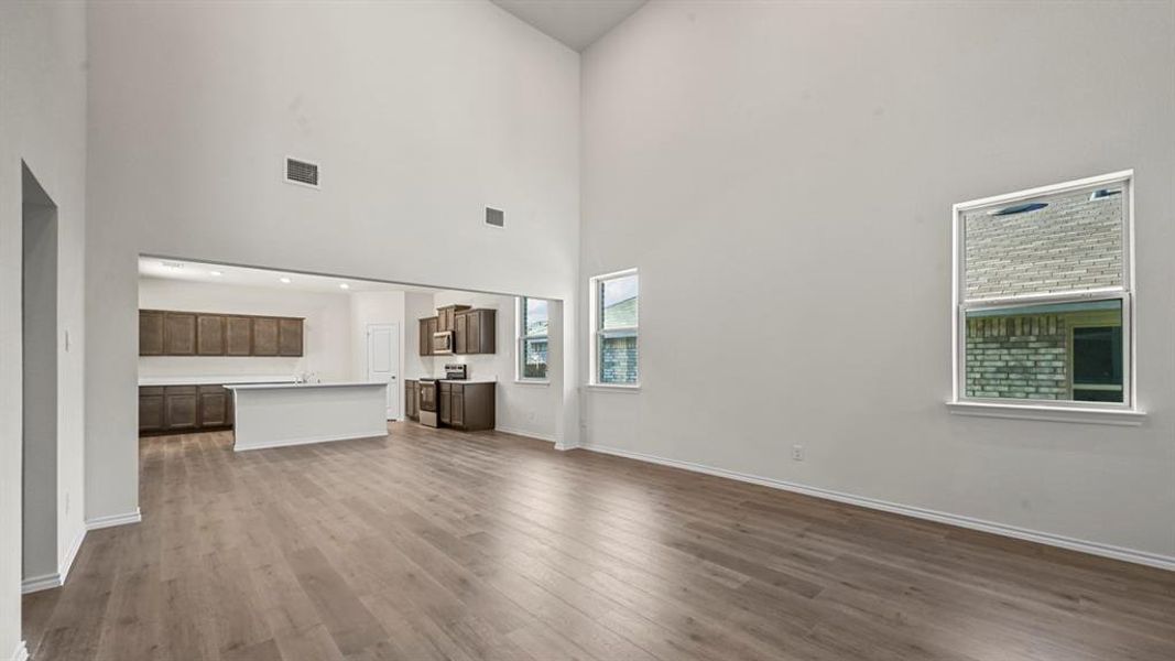 Spacious living area featuring high ceilings, wood-finish flooring, and multiple windows