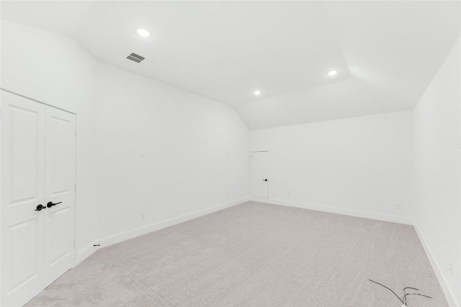 Empty bedroom with vaulted ceiling, carpet flooring, recessed lighting, and double closet doors
